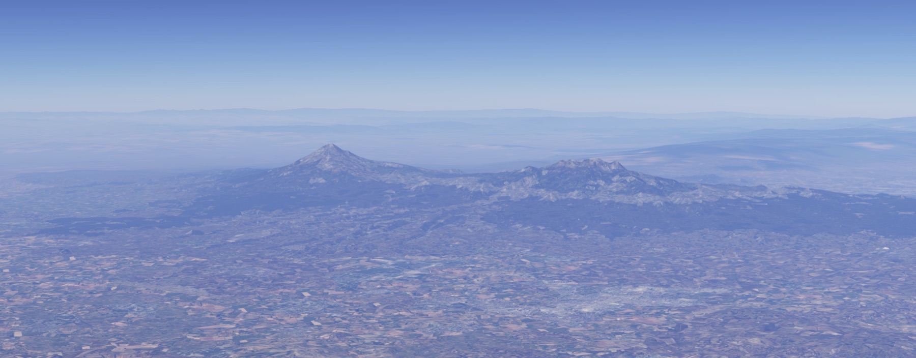 Dos volcanes sobre una llanura cultivada: a la izquierda un cono simétrico, a la derecha una cresta larga y dentada con varias cumbres.